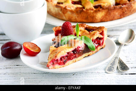 Stück hausgemachten Kuchen mit Pflaumen und dunkler Schokolade, dekoriert mit frischen Himbeeren und Bergamotte Stockfoto