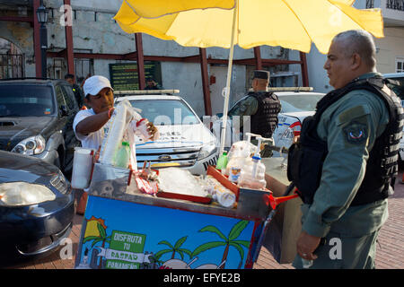 PANAMA CITY, PANAMA - Anbieter verkaufen Fruchtgeschmack rasiert Eis, bekannt als ein Raspado der Armee Soldat Polizei. Rasierte Eis ist ein l Stockfoto