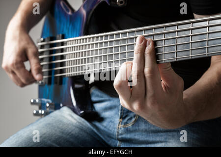 männliche Musiker spielen auf 6-Saiter e-Bass Stockfoto