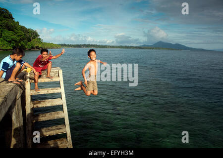 Jungen spielen und springen an Pier in Ozean auf Bunaken Island, Suawesi Stockfoto