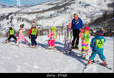 Acht junge erstmals Skifahrer nehmen Gruppenkurse mit einem Beaver Creek Ski School-Lehrer auf einen verschneiten Hang in den Bergen von Colorado, USA. Stockfoto