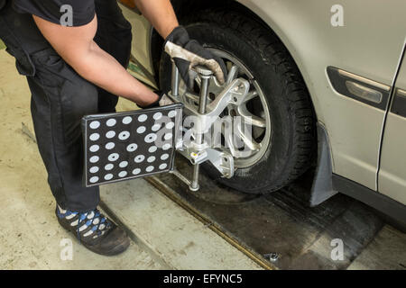 Ein Mechaniker stellt Ausrüstung auf einem Reifen vor Gleichgewicht der Vorspur-Winkel Stockfoto