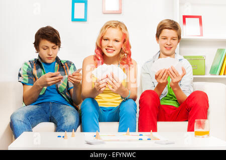Drei Jugendliche auf weißen Sofa Tischspiel spielen Stockfoto