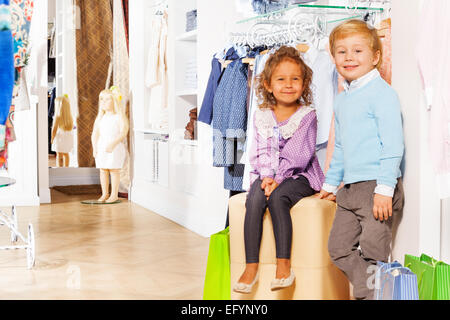 Steht jungen und Mädchen sitzt mit Einkaufstüten Stockfoto