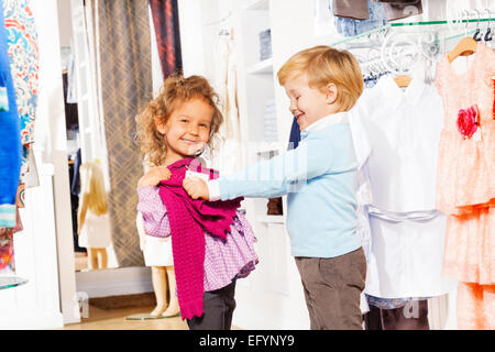 Fröhlicher Junge mit Mädchen passende Pullover im Shop Stockfoto