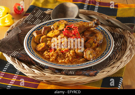 Jollof Reis mit gebratenem Huhn und Wegerich. Stockfoto