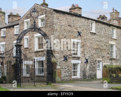 Schmiedeeiserne Tore, St. Marien Kirche in Kirkby Lonsdale, eine Marktstadt in Cumbria, zeigt die traditionellen Steinhäusern. Stockfoto