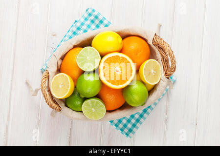 Zitrusfrüchte in Korb. Orangen, Limetten und Zitronen. Über Holztisch Hintergrund Stockfoto