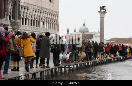 Im Bild: Touristen nutzen Gehwege, um trocken zu halten. Als der jährliche Karneval feiern losgehen, in Venedig, Hochwasser (Acqua Alta) viele Teile der Stadt überflutet. Viele Touristen wurden von den hohen Wassergehalt ertappt und musste kaufen verstärkten Kunststoff Stiefel in leuchtenden Farben - die über normale Schuhe - getragen werden, trocken zu halten. Besseres Wetter für den Karneval in Markusplatz entfernt dieses Wochenende prognostiziert. Stockfoto