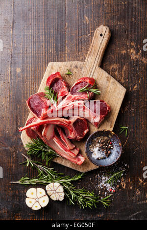 Rohes frisches Lammfleisch Rippen und Gewürze auf dunklem Holz Stockfoto