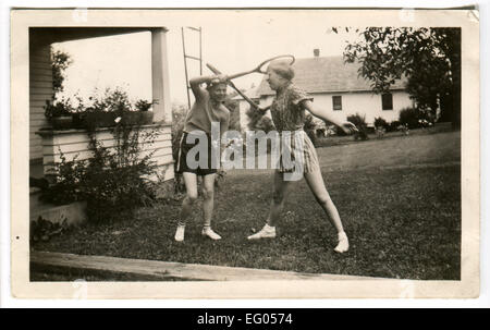 Kanada. 12. Dezember 2014. CA. 1940er Jahre: Reproduktion eines antiken Foto zeigt zwei Mädchen herumalbern, Vechta Tennisschläger auf der Wiese neben dem Haus © Igor Golovniov/ZUMA Draht/Alamy Live News Stockfoto