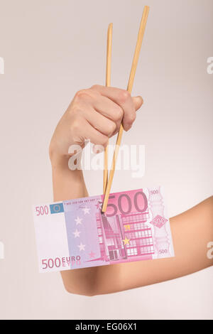 weibliche Hand mit Stäbchen und Euro-banknote Stockfoto