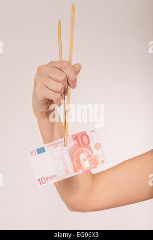 weibliche Hand mit Stäbchen und Euro-banknote Stockfoto