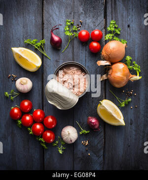 Dosen Thunfisch und Zutat für Tomatensauce mit Kräuter, Gewürze und Zitrone auf blauen hölzernen Hintergrund, Ansicht von oben Stockfoto