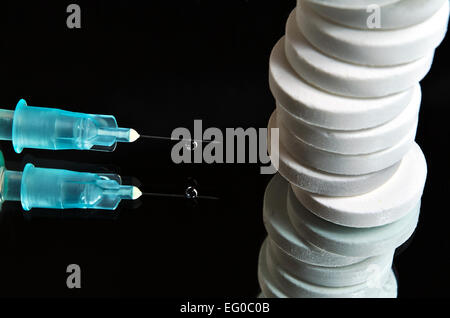 Pillen sind mit einer medizinischen Nadel mit einen Tropfen Flüssigkeit hängen übereinander gestapelt. Spiegelfläche Stockfoto