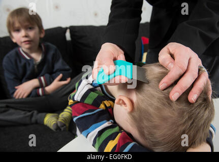 Mutter Überprüfung Childs Kopf für Läuse mit einem Kamm Stockfoto