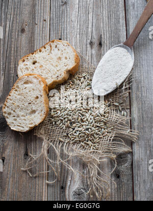 Roggen-Samen mit Scheiben Brot und Mehl in einem Holzlöffel Stockfoto