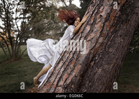 Schöne Frau umarmt einen Baum Stockfoto
