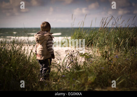 Kleiner Junge am Strand unter den Rasen Stockfoto