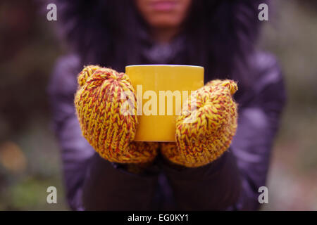 Hände mit Handschuhen halten Tasse Tee Stockfoto