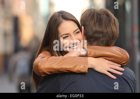 Porträt von einem glücklichen paar umarmt auf der Straße mit dem Gesicht der Frau im Vordergrund Stockfoto