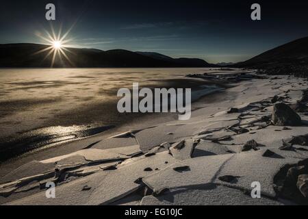 Die Sonne geht über einen gefrorenen Loch Glascarnoch im nordwestlichen Schottland. Stockfoto