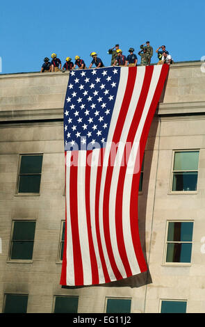 Militärangehörige gerendert Ehrungen wie die Feuerwehr und Rettungsdienst Arbeitnehmer entfaltet eine riesige amerikanische Flagge über die Seite des Pentagon 12. September 2001, während der Rettungs- und Arbeit nach dem Sept. 11 Terroranschlag. Der Angriff kam bei ca. 09:40, wie einem gekaperten Verkehrsflugzeug, mit Ursprung aus dem Dulles International Airport in Washington, D.C., in der südlichen Seite des Gebäudes in Richtung Virginia Highway 27 geflogen wurde.  von Michael W. Pendergrass Stockfoto