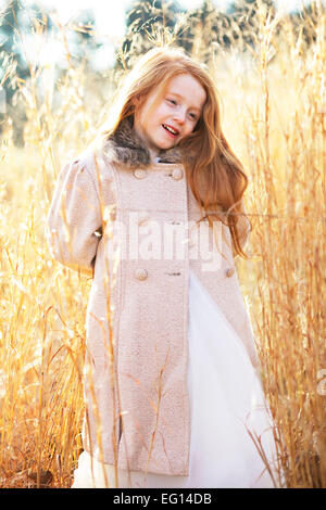 Lächelndes Mädchen mit Jacke im Feld hohem Gras Stockfoto