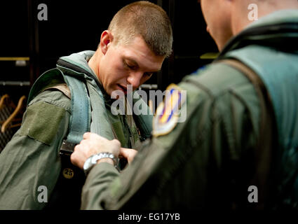 US Air Force Captain Chris Nations, ein 14. Fighter Squadron Standardisierung und Auswertungen Offizier, unterstützt Staff Sgt Bernard Mutz, einem 35. Bauingenieur-Geschwader Bereitschaft und Notfall-Manager mit seinem Flug Überlebensausrüstung im 14. FS Umkleideraum, Misawa Air Base, Japan, 22. Oktober 2010. Sergeant Mutz mit dem Sijean Award und 35. Mission Support Gruppe Flieger des Jahres 2009, verdienen sich einen Anreiz Flug in einem Flugzeug f-16 Fighting Falcon für seine Leistungen.  Staff Sgt Samuel Morse Stockfoto