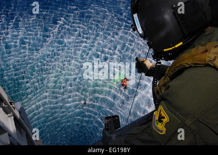 Senior Airman Jeremy Garrett senkt einen Rettungs-Korb nach unten in die wartenden Hände eine Pararescuemen unten während der Übung Keen Sword 6. Dezember 2010, auf der Kadena Air Base, Japan. Scharfen Schwert 2011 enthält eine geschätzte 10.500 US-Teilnehmer aus Heer, Marine, Luftwaffe und Marine. Airman Garrett ist ein Flugingenieur mit der 33. Rescue Squadron in Kadena.  Staff Sgt Lakisha A. Croley Stockfoto