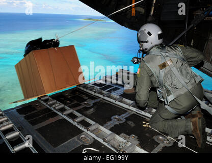 US Air Force Senior Airman Joseph Doria, ein 36. Airlift Squadron Loadmaster aus Yokota Air Base, Japan und Captain Stanley Kimball, ein 36. Airlift Squadron Fliegerarzt, sehen Sie eine Schachtel mit humanitärer Hilfe waren, die sie nur eine US Luftwaffe c-130 Hercules-Flugzeuge, Rufzeichen "Santa 23," Fallschirm hinunter seine Dropzone der Yap-Inseln 14 Dezember während der Operation Christmas Drop 2010 verdrängen. In diesem Jahr mehr als 60 Boxen, mit einem Gewicht von mehr als 20.000 Pfund insgesamt wird auf 55 Inseln gesunken.  Senior Airman Nichelle Anderson Stockfoto