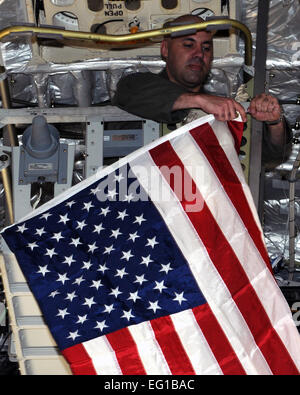 ALTUS AIR FORCE BASE in Oklahoma--Capt Jeremy J. Farlaino, 97. Training Squadron, Chef der Flügel Ausbildung hängt eine amerikanische Flagge aus dem Cat-Walk an Bord einer c-17 Globemaster III 22 März, vor dem Start, Operation Odyssey Dawn zu unterstützen. Capt Farlaino ist der Flugkapitän während dieser Mission.  Airman 1st Class Kenneth W. Norman / 97th Luft-Mobilität Flügel Öffentlichkeitsarbeit veröffentlicht. Stockfoto