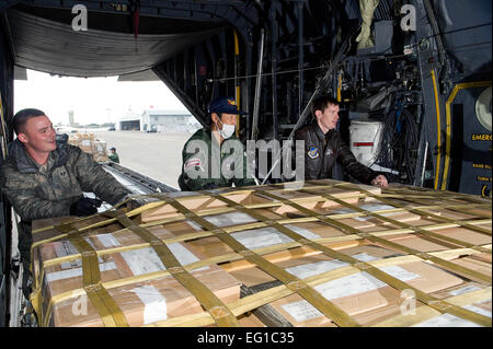 CHITOSE AIR BASE, Japan--US Air Force Staff Sgt Steven Sheeley links und rechts Capt Eric Elmore, 36. Airlift Squadron, mit der Hilfe von einem Mitglied der japanischen Defense Force push eine Palette auf eine c-130 in Chitose Air Base, März 29. Der c-130 ist humanitärer Güter und Zubehör für die japanischen Streitkräfte zur Unterstützung der Operation Tomodachi bekommen. /Master Sgt Jeromy K. Cross Stockfoto