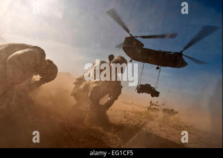 Army Staff Sgt Hector Hoyas und Air Force Senior Airman Matthew Phillips abwenden als eine Armee CH-47 Chinook Hubschrauber hebt ab mit einem Humvee Sling-Last 15. April 2011, während des Trainings am Nellis Air Force Base, Nevada Hoyas Fort-Schutze, Virginia Phillips zugeordnet ist das 820th RED HORSE-Geschwader zugewiesen ist.  Techn. Sgt. Michael R. Holzworth Stockfoto