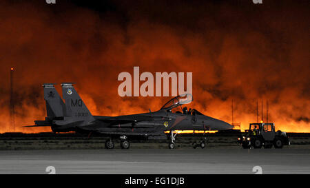 Ein Buschfeuer leuchtet am Abendhimmel hinter eine Republik der Singapur Luftwaffe F-15SG Jagdflugzeug 15. August 2011, bei Mountain Home Air Force Base, Idaho. Flightline Aktivität, sollen alle Flugbetrieb wurden gestoppt und Personal wurden von Flightline Gebäude evakuiert, als das Feuer die Basis näherten. Das Feuer brannte etwa 3.000 Hektar, darunter fünf Hektar großen Grundstück an der nordwestlichen Ecke der Basis.  Staff Sgt Gina Chiaverotti-Paige Stockfoto