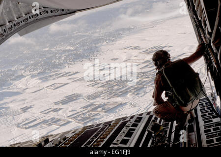 US Air Force Staff Sgt Christopher Bankston Uhren aus einer c-17 Globemaster III 3. März 2011, fällt als Luft Lieferung Fracht auf einer abgelegenen operative Basis in Afghanistan. Sergeant Bankston ist ein Loadmaster zur 816th Expeditionary Airlift Squadron versetzt.  Master Sergeant Adrian Cadiz Stockfoto