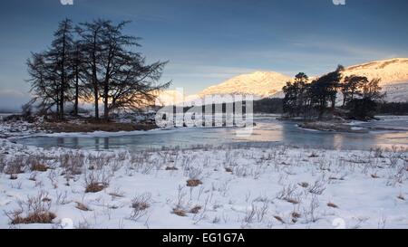 Erste Licht des Tages wirft einen goldenen Schimmer auf den Hügeln oberhalb von Rannoch Moor genommen von den Banken eine gefrorene Loch Tulla Stockfoto