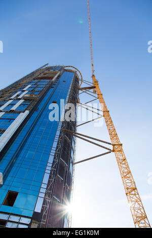 Riesiger Kran steigt in der Nähe von Bau eines Wolkenkratzers Stockfoto