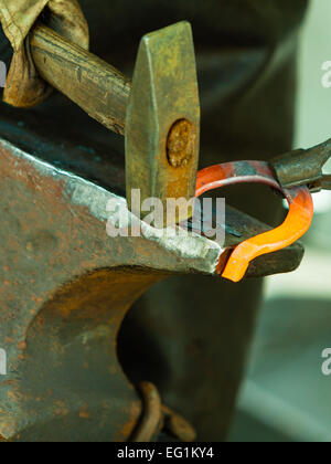 Machen dekoratives Element in der Schmiede auf dem Amboss. Glühenden Stahl hämmern. Schmied schmiedet ein heiße Hufeisen. Stockfoto