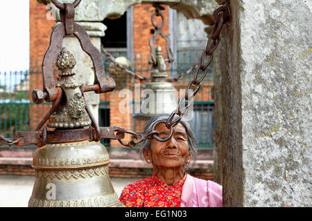 DHULIKHEL, NEPAL - 16 Oktober: Alte nepalesische Glöckner Frauenzimmerchen läutet die Glocken in unbekannten Tempel-W.part alten Dhulikhel Stockfoto