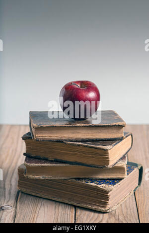 Stapel von Büchern und roter Apfel auf Holztisch. Textfreiraum Stockfoto