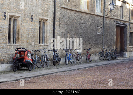 Fahrräder gegen eine bröckelnde Mauer stützte sich auf einen gepflasterten Stein Pflaster in Oxford Stockfoto