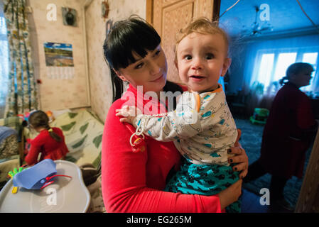 Tetiana Yakimova, 21 Jahre alte Witwe des Soldaten aus 95 luftbeweglichen Brigade Yakimov Alexander, starb in Kämpfe at13 Mai in der Nähe von Kramatorsk, ihr Sohn Timur, mit ihrer jüngeren Schwester und ihrer Mutter im Hintergrund halten. Radomyschl, Ukraine, 31. Januar 2015. Foto von Oleksandr Rupeta Stockfoto