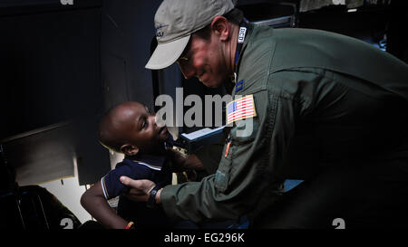 Capt Lindsey Kinsinger hilft, ein Kind ins Cockpit einer C-130J Super Hercules bei der Africa Aerospace und Defence Expo Waterkloof Air Force Base, South Africa, 20. September 2014.  Der c-130 aus die 37th Airlift Squadron war Teil eines Gesamt-Force-Teams von Guard, Reserve und Aktivaufgabe Soldaten und Piloten auf der Expo.  Staff Sgt Travis Edwards Stockfoto