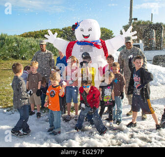 Major General Anthony Cotton hinten rechts, Chief Master Sgt. Herman Moyer zurück gelassen und Kinder ab dem 45. Space Wing genießen Sie echten Schnee während der Weihnachtsparty bei Patrick Air Force Base, Florida, 14. Dezember 2012. Baumwolle ist der 45. SW Kommandant und Moyer ist der 45. SW Befehl Chef. Stockfoto