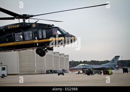 Ein U.S. Customs and Border Protection UH-60 Black Hawk Hubschrauber hebt ab, wie eine F - 16C Fighting Falcon von der New Jersey Air National Guard 177. Kämpfer-Flügel im Hintergrund geparkten am 28. Jan. in Atlantic City Air National Guard Base, N.J.  Die US Customs and Border Protection verbrachte den Tag informieren die Medien über die Rolle, die sie als Bestandteil der Gesamtkraft Aufwand für Sicherheit am Super Bowl XLVIII spielen werden.   Techn. Sgt. Matt Hecht Stockfoto