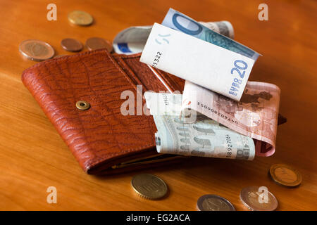 Geldbeutel und etwas Geld auf einem Holztisch verstreut Stockfoto