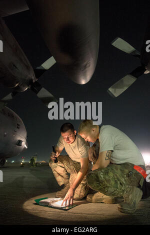 Staff Sgt Kyle Law and Staff Sgt Joshua Jorgensen, 774th Expeditionary Airlift Squadron Crew Chiefs, wenden Sie sich an eine technische, um eine C - 130 H Hercules Motor Problembehandlung bei Bagram Airfield, Parwan Provinz, Afghanistan, 6. Oktober 2013. Herkules Aircrew 774th EAS geliefert 32 Cargo bündeln auf zwei Reisen zu entfernten Dropzonen in Provinz Ghazni, Afghanistan. Gesetz, San Antonio, Texas geboren, und Jorgensen, Brentwood, Kalifornien stammende werden von Little Rock Air Force Base, Arche USAF Foto/Master Sergeant Ben Bloker eingesetzt. Stockfoto