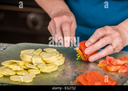 Frau Vorbereitung Veggie Pizzabelag Autokamp Tomate, in Scheiben geschnitten Sommerkürbis und geröstete Paprika. Stockfoto