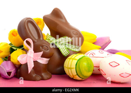 Glückliches Ostern Schokolade Hase Kaninchen mit rosa, weiße und grüne Eiern auf Vintage rosa Holz Hintergrund. Stockfoto